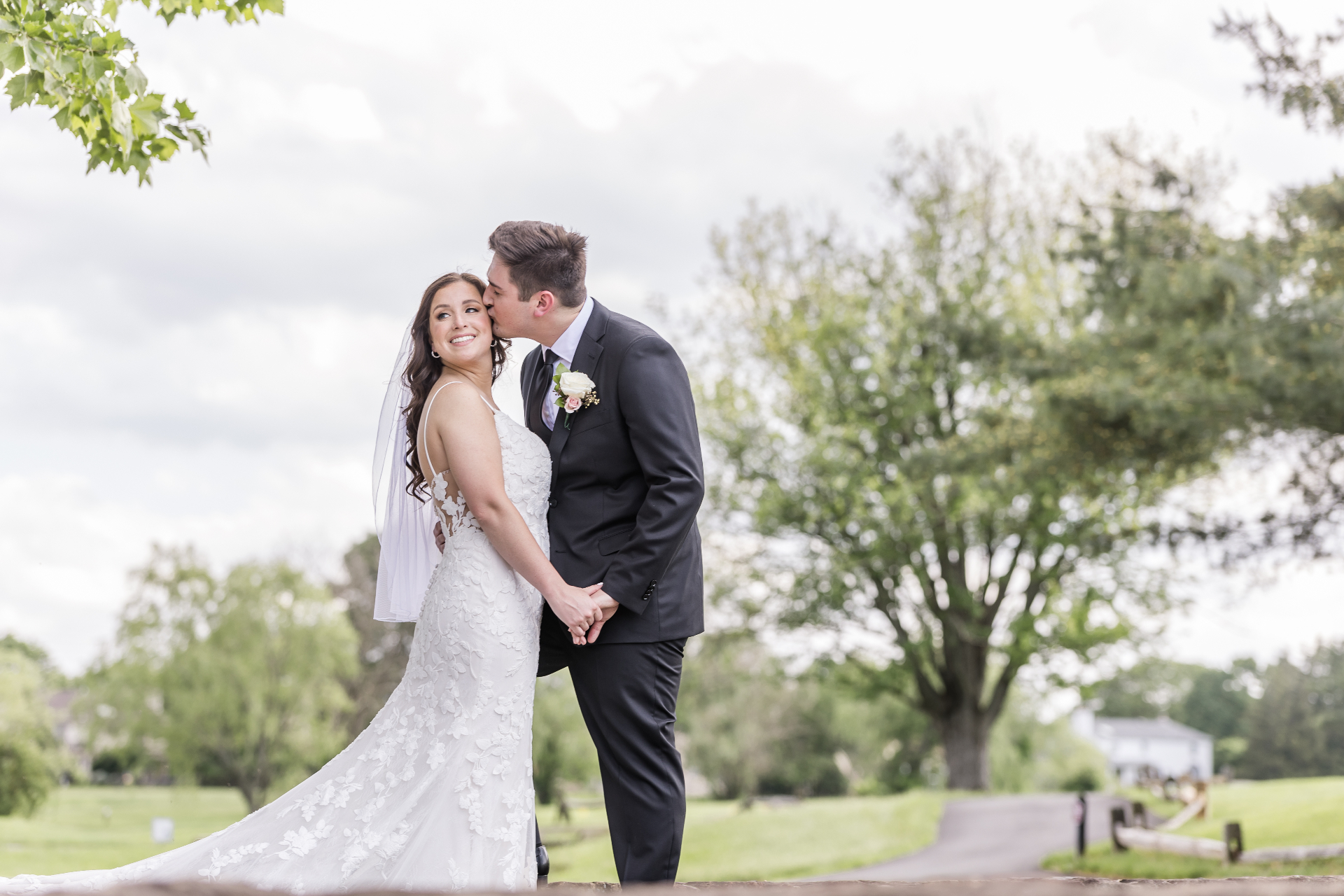 Groom kissing bride on the forehead on the grounds of The Arbor